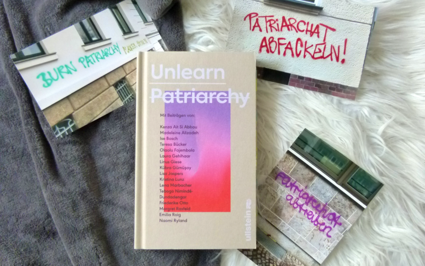 Das Buch liegt auf einem grauen und weißen Stoff-Untergrund. Um das Buch herum liegen drei Fotografien, die Graffities zeigen: "Burn Patriarchy", "Patriarchat abfackeln" und "Patriarchat abtreiben" steht an den Wänden