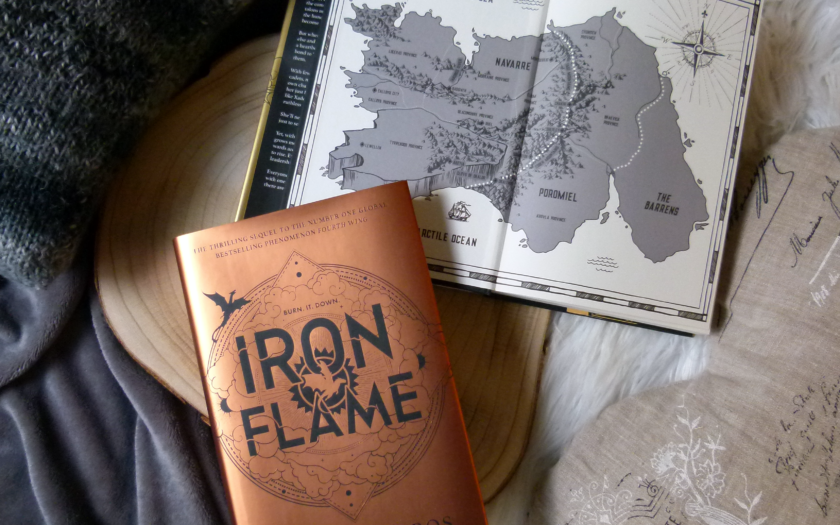 Das Buch liegt auf einer Holzscheibe und diese auf einer grauen und einer weißen Decke. Über dem Buch liegt aufgeschlagen die Karte von Navarre.