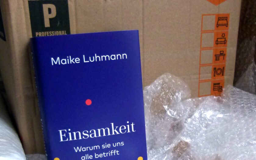 Das Buch steht vor einer Umzugskiste. Darumherum liegt Luftpolsterfolie