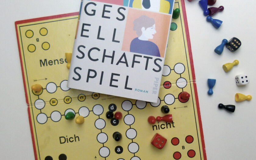 Das Buch liegt auf einem "Mensch-ärgere-dich-nicht"-Spielbrett mit umgeworfenen Spielfiguren und Würfeln.